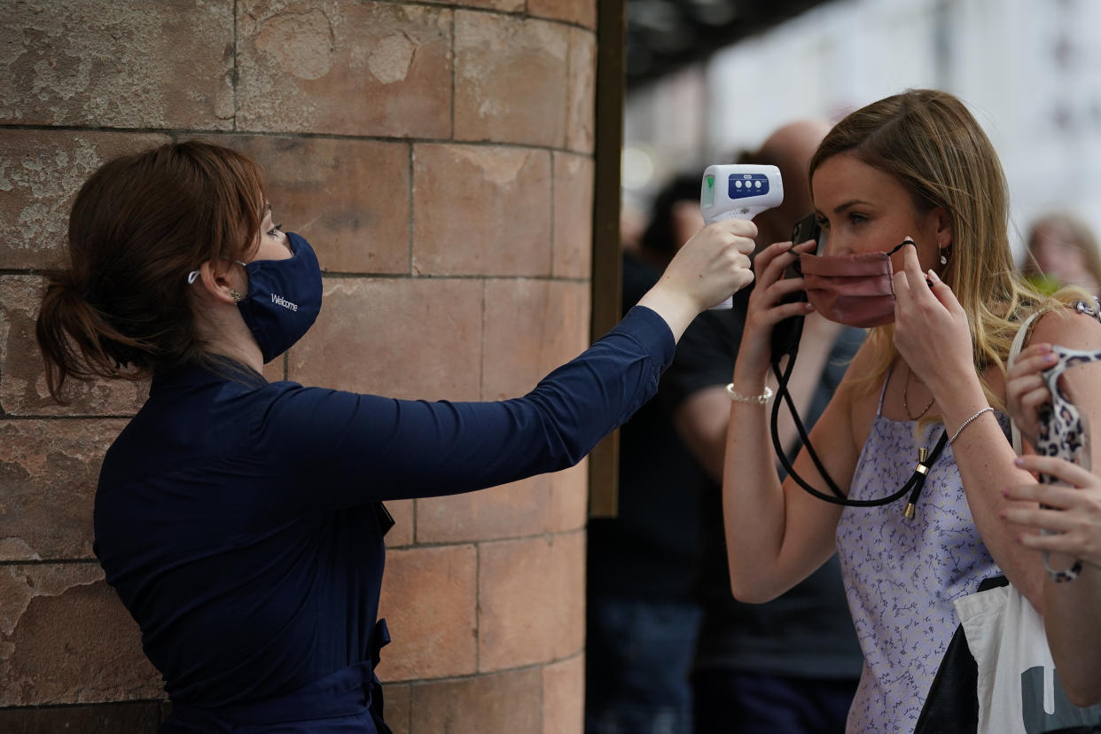 A woman has her temperature checked in the queue for The Show Must Go On Live at the Palace Theatre in London. Picture date: Wednesday June 2, 2021.