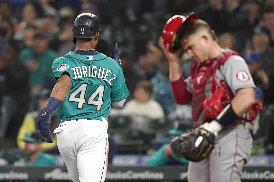 Seattle Mariners' Julio Rodriguez reacts as he crosses the plate in front of Los Angeles Angels catcher Max Stassi, right, scoring a run on an RBI-single hit by Eugenio Suarez during the first inning of a baseball game, Friday, June 17, 2022, in Seattle. (AP Photo/Ted S. Warren)