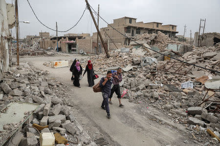 Displaced Iraqi people walks past destroyed buildings during the battle between the Iraqi Counter Terrorism Service and Islamic State militants in western Mosul, Iraq, April 23, 2017. REUTERS/Marko Djurica