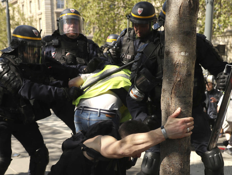 A police officer scuffle with protestors during a yellow vest demonstration in Paris, Saturday, April 20, 2019. French yellow vest protesters are marching anew to remind the government that rebuilding the fire-ravaged Notre Dame Cathedral isn't the only problem the nation needs to solve. (AP Photo/Francisco Seco)