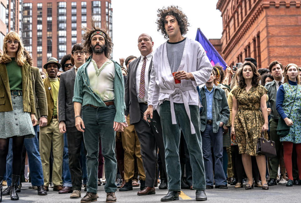 En esta imagen proporcionada por Netflix, al frente de izquierda a derecha, Caitlin Fitzgerald, Jeremy Strong y Sasha Baron Cohen en una escena de "The Trial of the Chicago 7", nombrada entre las 10 películas del año por The American Film Institute. (Nico Tavernise/Netflix via AP)