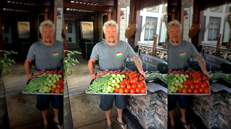 Guy Fieri holding a tray of vegetables