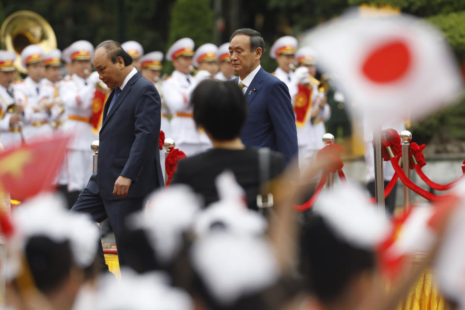 Japanese Prime Minister Yoshihide Suga, center right, and his Vietnamese counterpart Nguyen Xuan Phuc, center left, attend a welcoming ceremony at the Presidential Palace in Hanoi, Vietnam Monday, Oct. 19, 2020. (Kham/Pool Photo via AP)