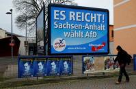 A man walks past an election poster of the right-wing Alternative for Germany (AfD) party reading 'That's enough! Saxony-Anhalt votes AfD' in the city of Magdeburg in Saxony-Anhalt, Germany, March 13, 2016. REUTERS/Wolfgang Rattay