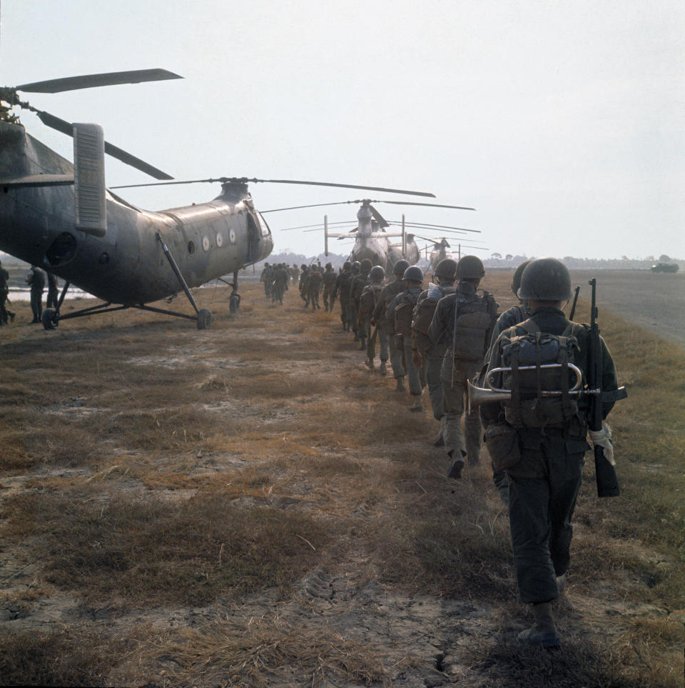 South Vietnamese troops, one with a bugle strapped to his pack, line up to board CH-21 Flying Banana helicopters, March 1963. (AP Photo/Horst Faas)