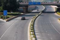 A small number of motorists make their way along a deserted street during a one-day Janata (civil) curfew imposed as a preventive measure against the COVID-19 coronavirus in New Delhi on March 22, 2020. - Nearly one billion people around the world were confined to their homes, as the coronavirus death toll crossed 13,000 and factories were shut in worst-hit Italy after another single-day fatalities record. (Photo by Jewel SAMAD / AFP) (Photo by JEWEL SAMAD/AFP via Getty Images)