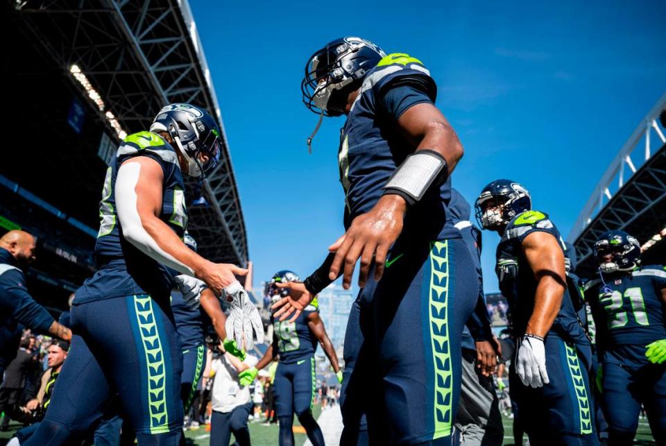 Seattle Seahawks quarterback Geno Smith (7) high-fives Seattle Seahawks linebacker Tanner Muse (58) as they run onto the field to warm up before the start of an NFL game at Lumen Field in Seattle, Wash. on Sept. 25, 2022.