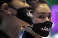 Receptionists wearing face masks carrying the car brand to help curb the spread of the coronavirus at the Auto China 2020 show in Beijing, Sunday, Sept. 27, 2020. Auto China 2020, postponed from March, is the first major trade show for any industry since the pandemic began as automakers are looking to China, the first major economy to start recovering from the coronavirus pandemic, to drive sales growth and reverse multibillion-dollar losses. (AP Photo/Andy Wong)