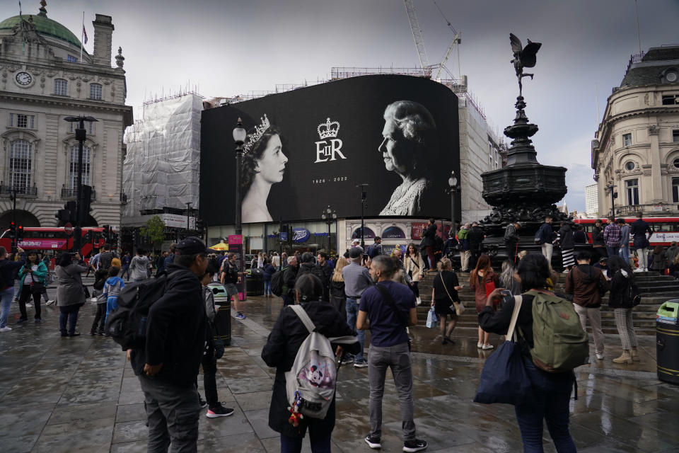 People look at a black and white tribute to the Queen at Piccadilly Circus in London, Friday, Sept. 9, 2022. Queen Elizabeth II, Britain's longest-reigning monarch and a rock of stability across much of a turbulent century, died Thursday Sept. 8, 2022, after 70 years on the throne. She was 96. (AP Photo/Alberto Pezzali)