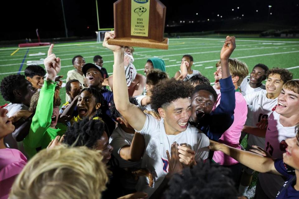 Lafayette senior Sawyer Trowel holds up the 43rd District boys soccer championship trophy as he celebrates with teammates after the Generals defeated Paul Laurence Dunbar in overtime at Tates Creek High School on Oct. 4.