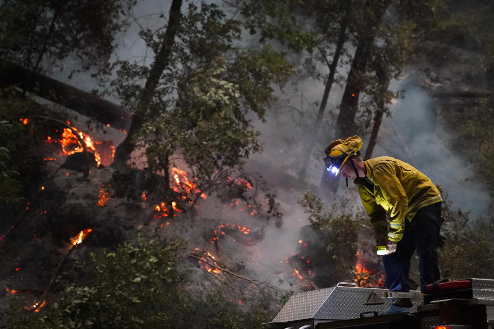 Ben Slaughter, a firefighter for the Boulder Creek Fire Department, stands on top of a fire truck along Highway 9 while monitoring flames from the CZU August Lightning Complex Fire, Saturday, Aug. 22, 2020, in Boulder Creek, Calif. (AP Photo/Marcio Jose Sanchez)
