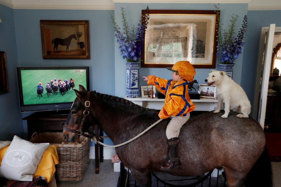 Horse Racing - Merlin Coles, 3, watches horse racing from Royal Ascot on TV at his home - Bere Regis, Britain - June 17, 2020 Merlin Coles 3, watches the horse racing from Royal Ascot on TV at his home, whilst sat on his horse Mr Glitter Sparkles with his dog Mistress, in Bere Regis, Dorset, as racing resumed behind closed doors after the outbreak of the coronavirus disease (COVID-19) REUTERS/Paul Childs