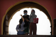 People wearing face masks to protect against the coronavirus take photos at the Temple of Heaven in Beijing, Saturday, July 18, 2020. Authorities in a city in far western China have reduced subways, buses and taxis and closed off some residential communities amid a new coronavirus outbreak, according to Chinese media reports. They also placed restrictions on people leaving the city, including a suspension of subway service to the airport. (AP Photo/Mark Schiefelbein)