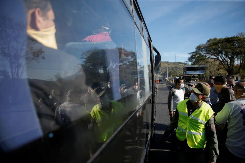 A member of the Bolivarian National Guard checks if people onboard a bus are wearing their protective masks before allowing them to pass through a checkpoint into Caracas