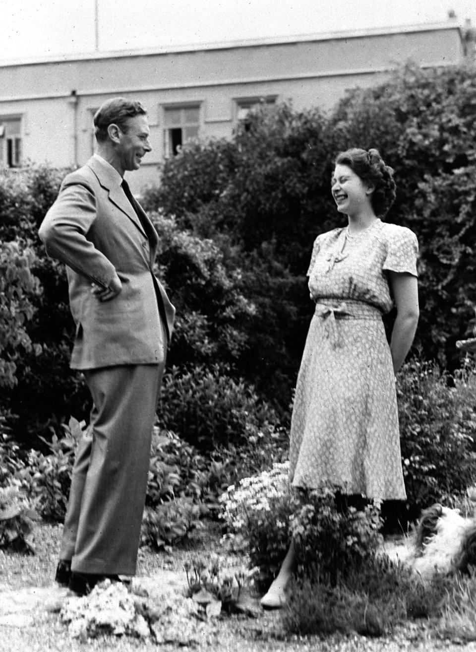 FILE - Britain's Queen Elizabeth II, then Princess Elizabeth, right, reacts with her father King George VI, in the grounds of the Royal Lodge, Windsor, England, Aug. 20, 1946. Queen Elizabeth II will mark 70 years on the throne Sunday, Feb. 6, 2022, an unprecedented reign that has made her a symbol of stability as the United Kingdom navigated an age of uncertainty. (AP Photo, File)