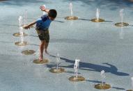 <p>One person uses the CityScape splash pad to stay cool as temperatures climb to near-record highs, June 20, 2017, in Phoenix. (Ross D. Franklin/AP) </p>