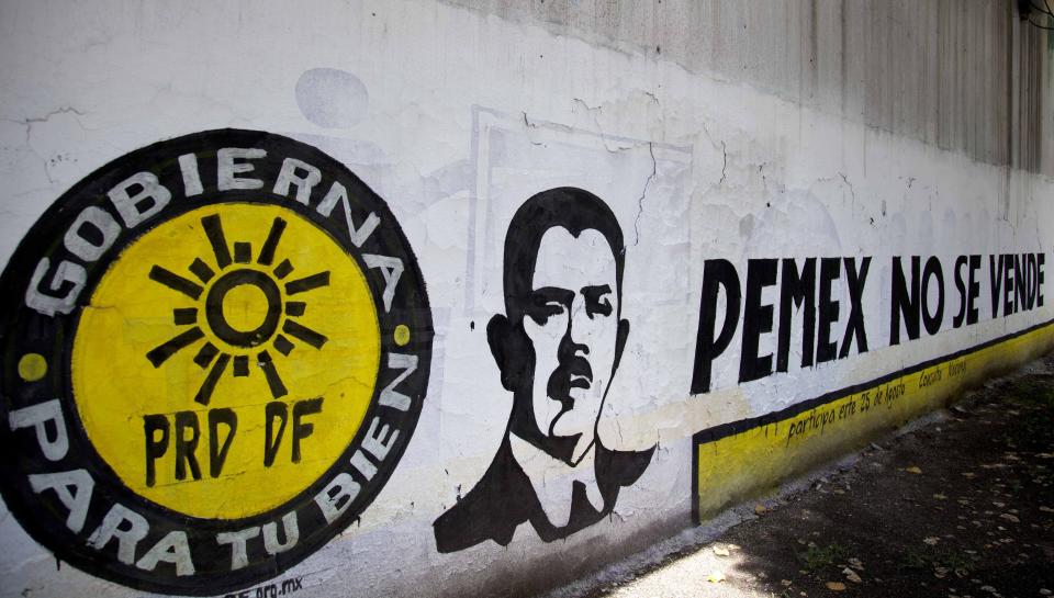 FILE - A mural of Mexico's former President Lazaro Cardenas covers a wall alongside the words in Spanish "Pemex is not for sale," right, from the PRD political party in Mexico City, Friday, Aug. 16, 2013. Cardenas' oil expropriation was the single most popular decision by a Mexican president in the 20th century, and the nationalization remains immensely popular. (AP Photo/Eduardo Verdugo, File)