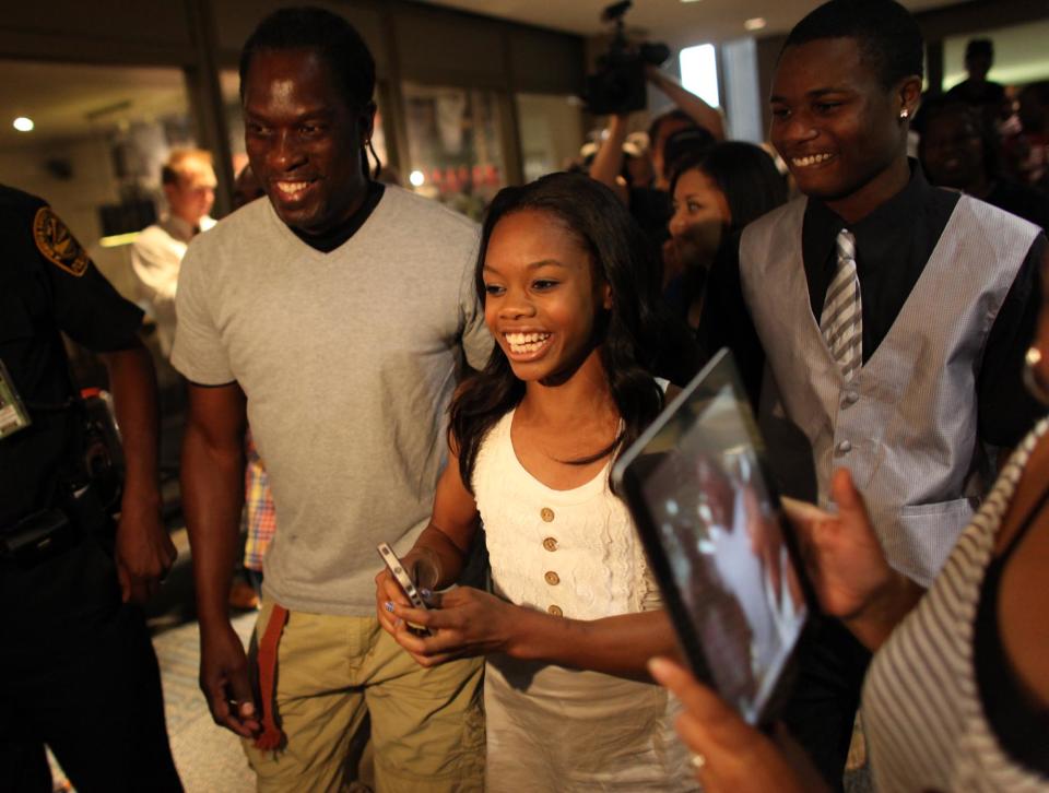 Greeted and accompanied by friends and family, 2012 Olympic gymnast and Gold medal winner Gabby Douglas arrives at the Norfolk, Va. Airport on Thursday evening, Aug. 16, 2012, on a visit to hometown of Virginia Beach, Va. (AP Photo/The Virginian-Pilot, Ross Taylor)