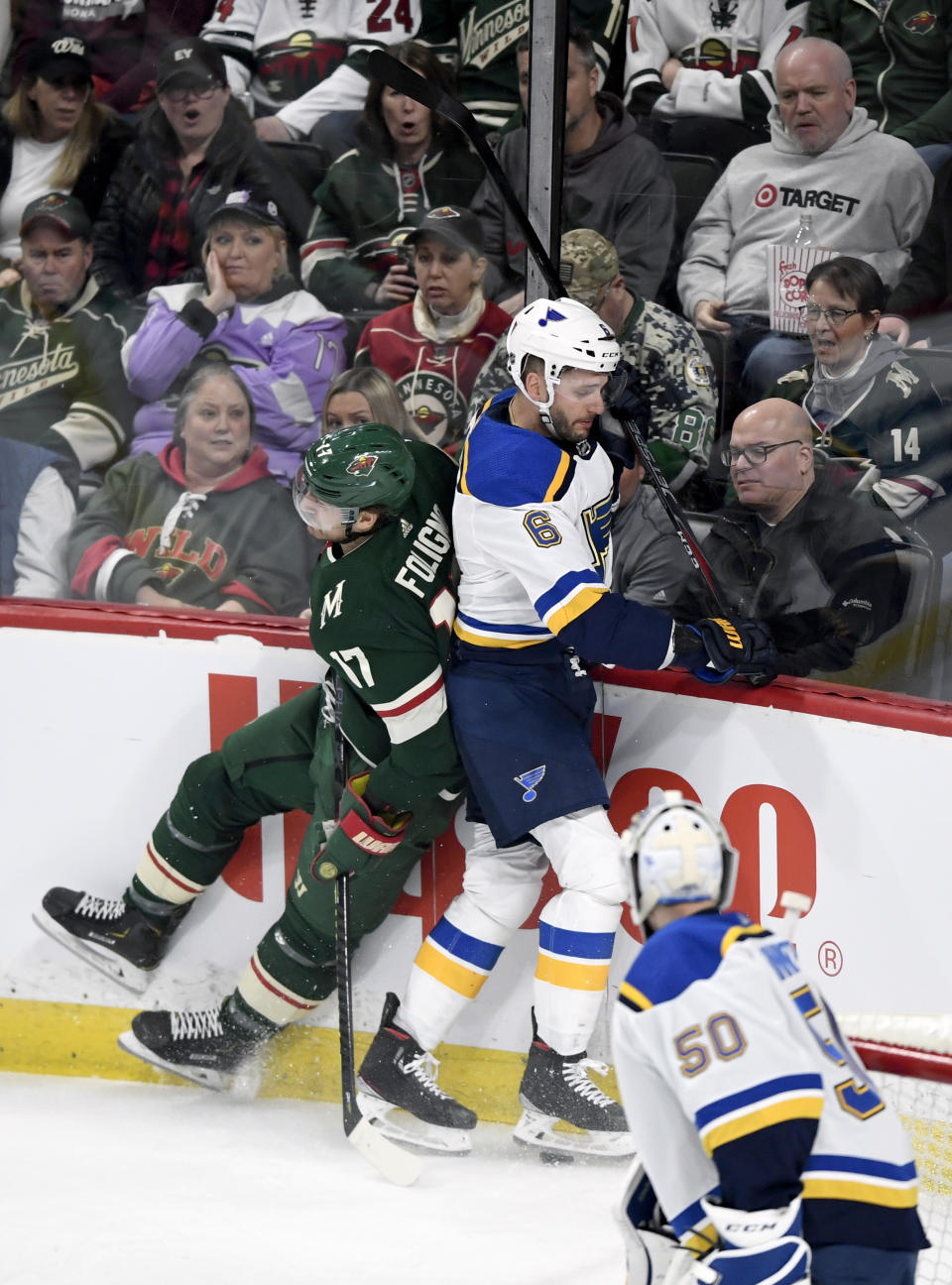 St. Louis Blues goaltender Jordan Binnington (50) watches as Minnesota Wild's Marcus Foligno (17) checks St. Louis Blues' Marco Scandella (6) during the first period of an NHL hockey game Sunday, Feb. 23, 2020, in St. Paul, Minn. (AP Photo/Hannah Foslien)