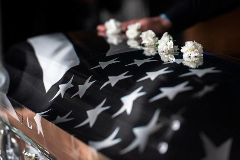 Mourners lay white flowers on the caskets of Bay St. Louis police officers Sgt. Steven Robin and Branden Estorffe at Gardens of Memory cemetery in Bay St. Louis on Wednesday, Dec. 21, 2022. Robin and Estorffe were killed responding to a call at a Motel 6 on Dec. 14.