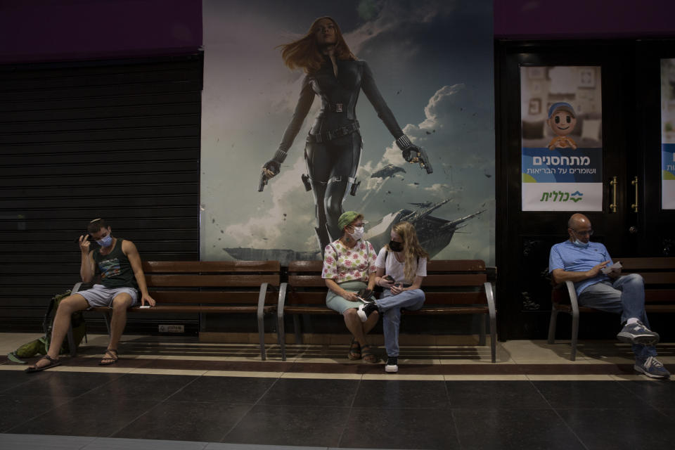 FILE - In this Aug. 15, 2021, file photo, Israelis wait their turn for a booster shot of the coronavirus vaccine, at Clalit Health Services, one of Israel's health maintenance organizations, at a cinema complex, in Jerusalem. Israel is pressing ahead with its aggressive campaign of offering coronavirus boosters to almost anyone over 12 and says its approach was further vindicated by a U.S. decision to give the shots to older patients or those at higher risk. (AP Photo/Maya Alleruzzo, File)