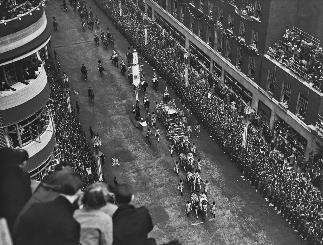 The Gold State Coach, in which George VI and Queen Elizabeth are riding, as it passes along a street lined with crowds of well-wishers en route to their coronation ceremony, held at Westminster Abbey in London, on May 12, 1937.