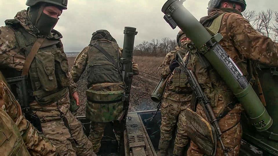 Three Russian soldiers ride on an armored vehicle.