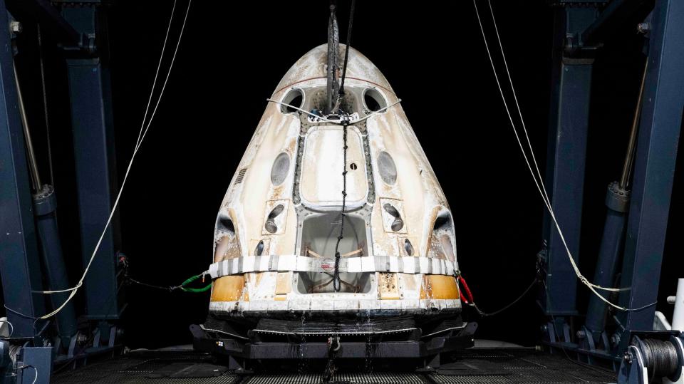 white space capsule rests on the deck of a recovery ship