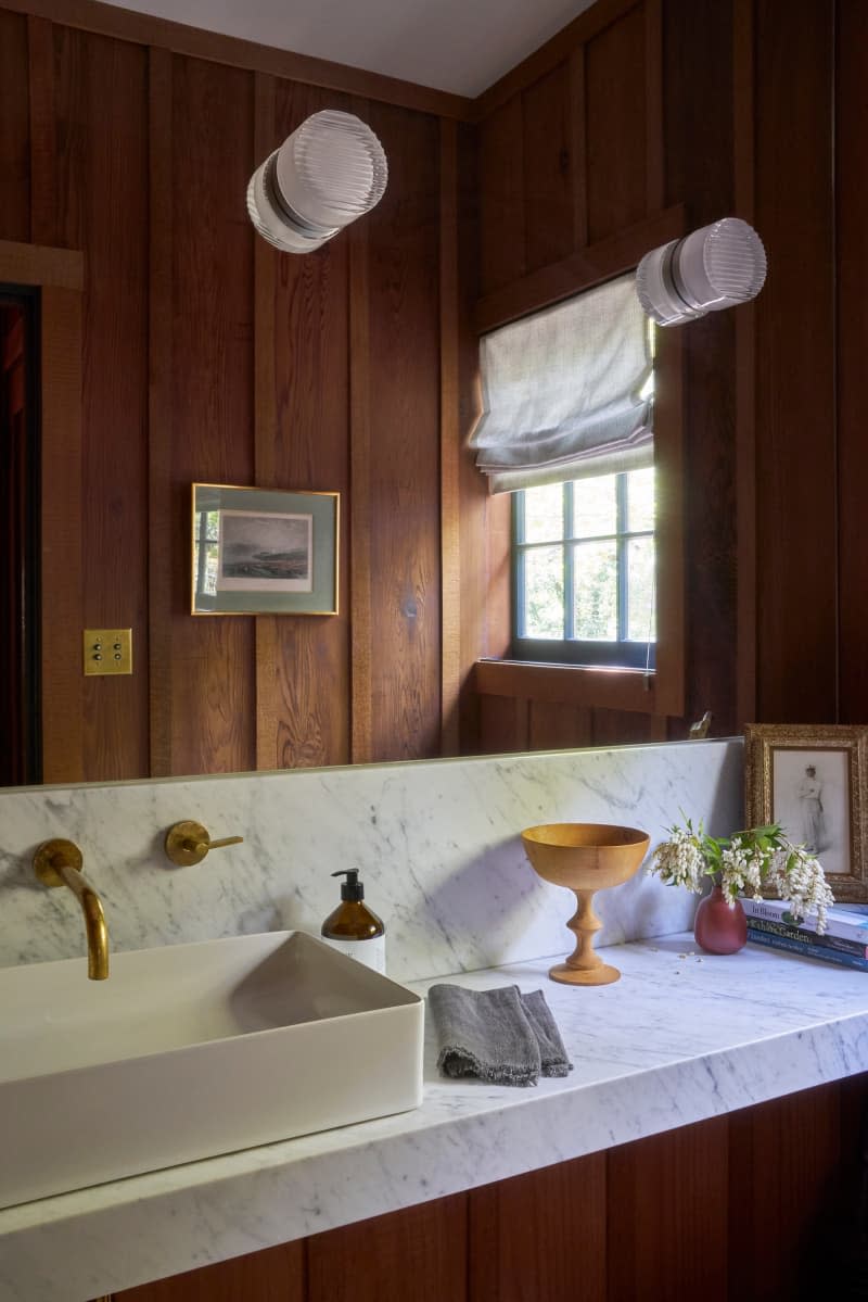 Marble vanity top in wood paneled bathroom.