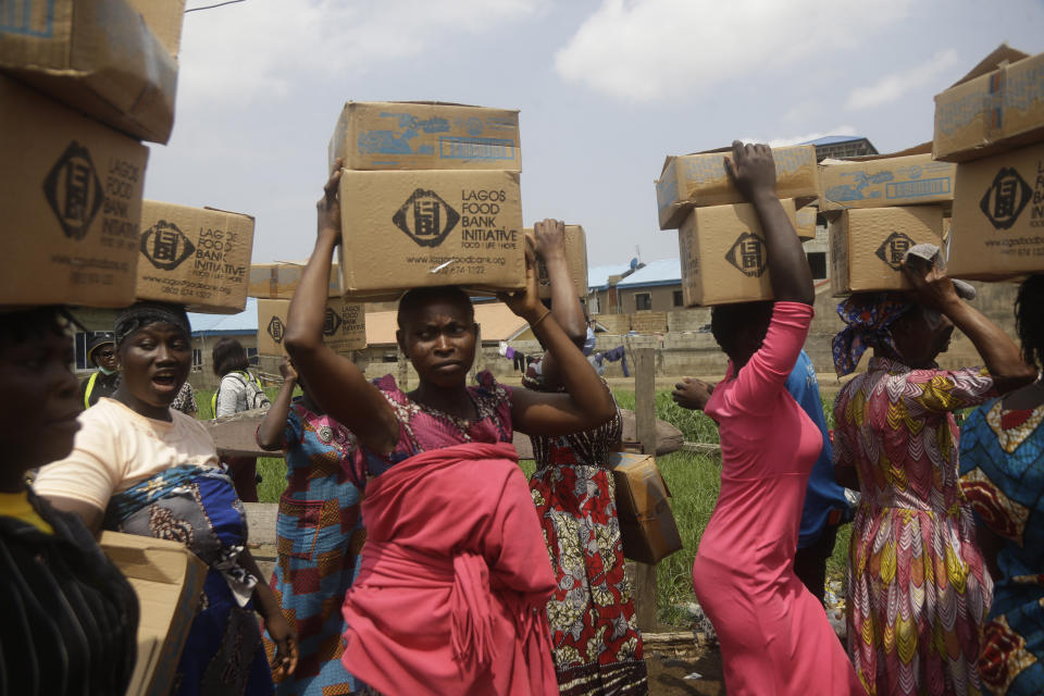 FILE - Residents of Oworonshoki Slum carry their food parcels distributed by the Lagos Food Bank Initiative, a non-profit nutrition focused initiative committed to fighting hunger and solving problems of Malnutrition for poor communities, in Lagos, Nigeria, Saturday, July 10, 2021. Two U.N. food agencies issued stark warnings on Monday, June 6, 2022 about multiple, looming food crises on the planet, driven by climate “shocks” like drought and worsened by the repercussions of the COVID-19 pandemic and the war in Ukraine that have sent fuel and food prices soaring. (AP Photo/Sunday Alamba, File)