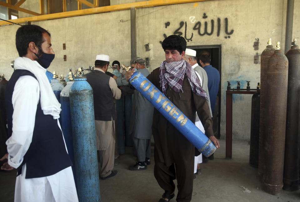 A man carries an oxygen tank from a privately owned oxygen factory, in Kabul, Afghanistan, Thursday June 18, 2020. For seven years, Najibullah Seddiqi's oxygen factory sat idle in the Afghan capital Kabul. He shut it down, he says, because corruption and power cuts made it impossible to work. But when the novel coronavirus began racing through his country, he opened the factory's dusty gates and went back to work. Now he refills hundreds of oxygen cylinders a day for free for COVID-19 patients — and at reduced rates for hospitals. (AP Photo/Rahmat Gul)