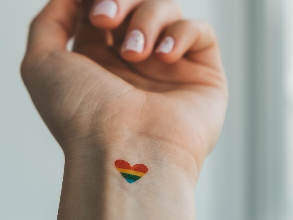 small rainbow heart tattooed on the inside of someone's wrist