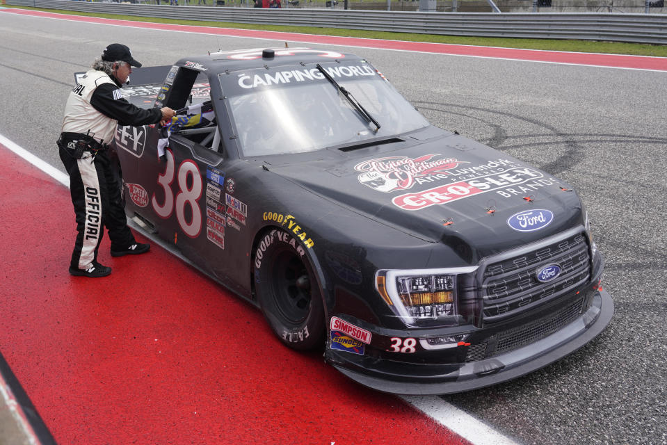 A NASCAR official hands the checkered flag to Todd Gilliland after Gilliland won the NASCAR Truck Series auto race at the Circuit of the Americas in Austin, Texas, Saturday, May 22, 2021. (AP Photo/Chuck Burton)