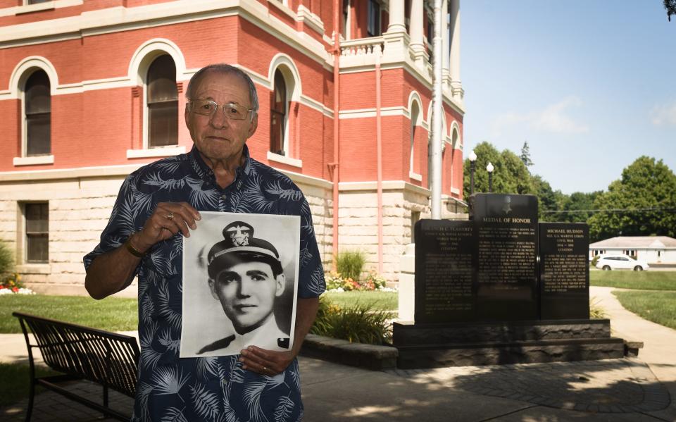 Don Colizzi of Charlotte holds a photograph of the late U.S. Navy Ensign Francis Flaherty, Tuesday, Aug. 10, 2021, near the Medal of Honor monument honoring Flaherty, a World War II veteran, and Civil War veteran USMC Sgt. Michael Hudson. The two are the only Charlotte residents known to have earned the Medal of Honor, America's highest military decoration. Colizzi was instrumental in raising funds for the monument at the 1885 Eaton County Courthouse.