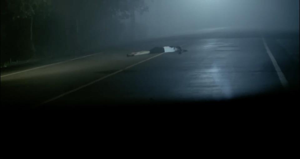 A person lying on a dark highway