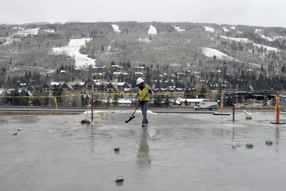 FILE - A construction worker sweeps ice and debris from an unfinished floor of an affordable housing project in the ski resort town of Vail, Colo., on Oct. 25, 2022. While cities are are typically left to fend off sky-high housing prices, Colorado lawmakers are wading into the crisis with a proposal to free up vacant parcels of state-owned land that could be leased or sold at a discount for affordable housing projects. (AP Photo/Thomas Peipert, File)