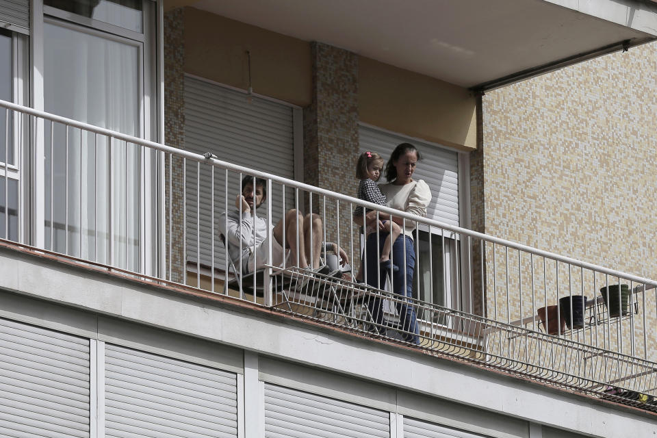 FILE - In this March 19, 2020, file photo, people look out from their balcony in Madrid, Spain. Residents are snitching on businesses and neighbors as authorities worldwide work to enforce business shutdowns and stay-at-home orders meant to limit person-to-person contact amid the coronavirus pandemic. Police in Spain, sometimes aided by videos and photos posted online by zealous citizens, or “balcony police”, have arrested nearly 2,000 people and fined over 230,000 for violating quarantine orders. (AP Photo/Manu Fernandez, File)