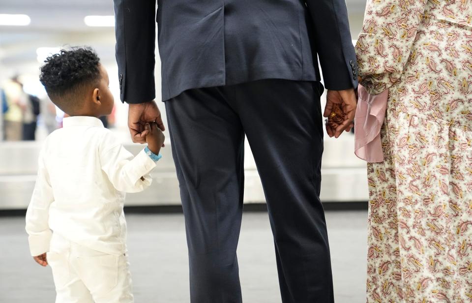 Afkab Hussein holds the hand of his wife, Rhodo Abdirahman, and youngest son, Zain, 2, who arrived from Kenya at the John Glenn Columbus International Airport on Thursday.