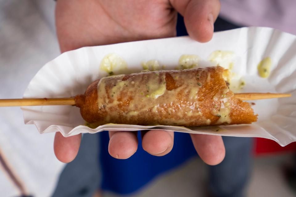 Professional chefs Alex Carter, owner of Black Cat Ice Cream, and Rateb Aburas, Rateb Aburas, executive chef of Mulberry Street Tavern and the Surety Hotel Des Moines, try a rattlesnake corn dog from Pioneer Wagon at the Iowa State Fair.