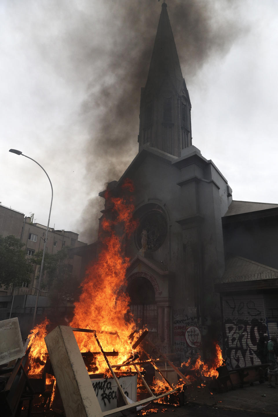 Items removed from a church by anti-government protesters go up in flames in a barricade they built, in Santiago, Chile, Friday, Nov. 8, 2019. Chile's president on Thursday announced measures to increase security and toughen sanctions for vandalism following three weeks of protests that have left at least 20 dead. (AP Photo/Esteban Felix)