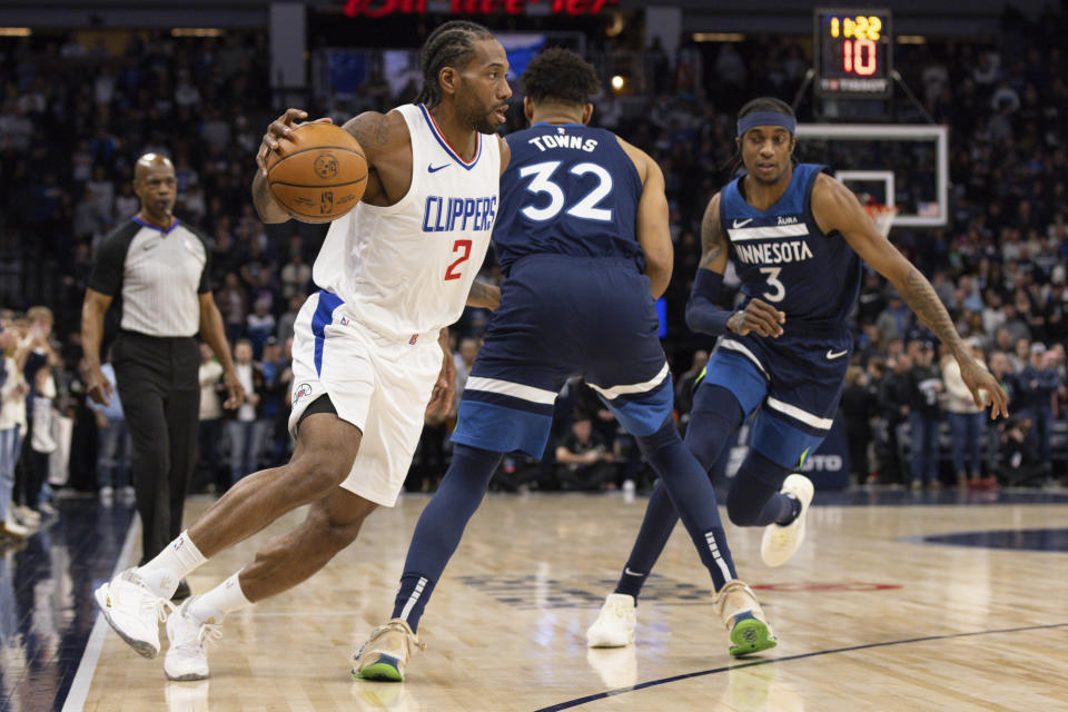 Los Angeles Clippers forward Kawhi Leonard (2) drives to the basket around Minnesota Timberwolves center Karl-Anthony Towns (32) and forward Jaden McDaniels (3) during the first half of an NBA basketball game, Sunday, Jan. 14, 2024, in Minneapolis, Minn. (AP Photo/Bailey Hillesheim)