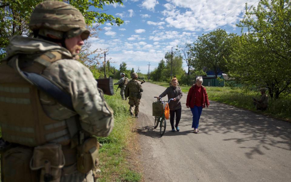 Local women walk along a street while Ukrainian soldiers patrol the area, as Russia's attack on Ukraine continues, in the town of Kurakhove, in Donetsk region - REUTERS/Anna Kudriavtseva