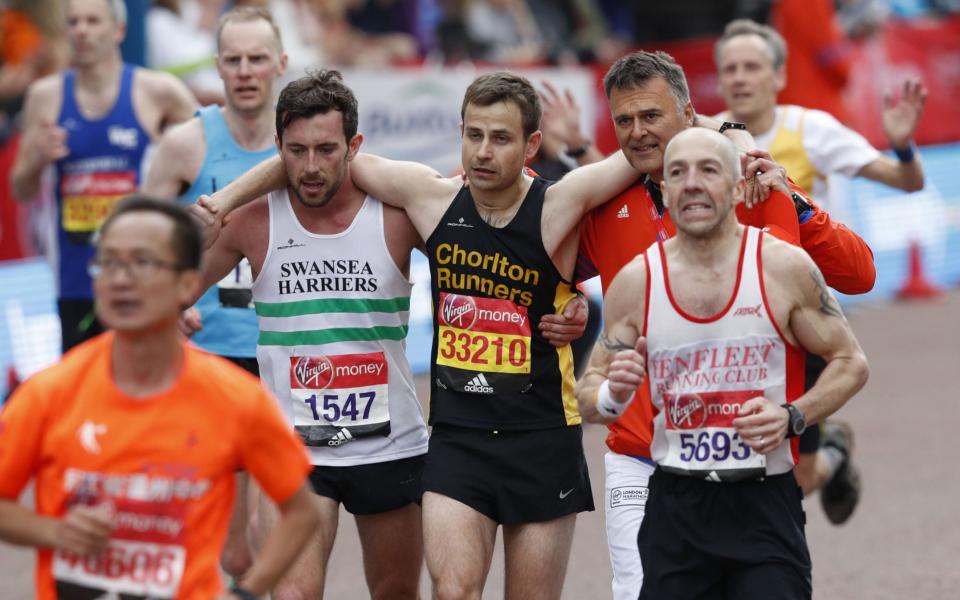 Matthew Rees helped another runner over the line - Credit: ADRIAN DENNIS/AFP 