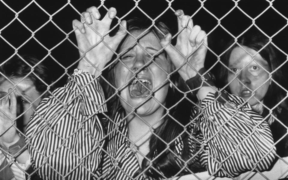 A hysterical fan grasps a wire fence at a David Cassidy concert at White City, West London, 1974; one teenager died and 700 others were injured - Getty