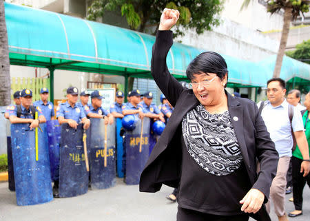 Judy Taguiwalo, a left-wing activist who was jailed during the 1970s martial law era of late dictator Ferdinand Marcos, clenches her fist while walking past anti-riot police officers, after Philippine lawmakers rejected the appointment of her as social welfare minister during a Commission on Appointment hearing at the Senate headquarters in Pasay City, Metro Manila, Philippines August 16, 2017. REUTERS/Romeo Ranoco