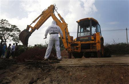 A police officer watches as an excavator digs up skeletons at a construction site in the former war zone in Mannar, about 327 km (203 miles) from the capital Colombo, January 16, 2014. REUTERS/Dinuka Liyanawatte