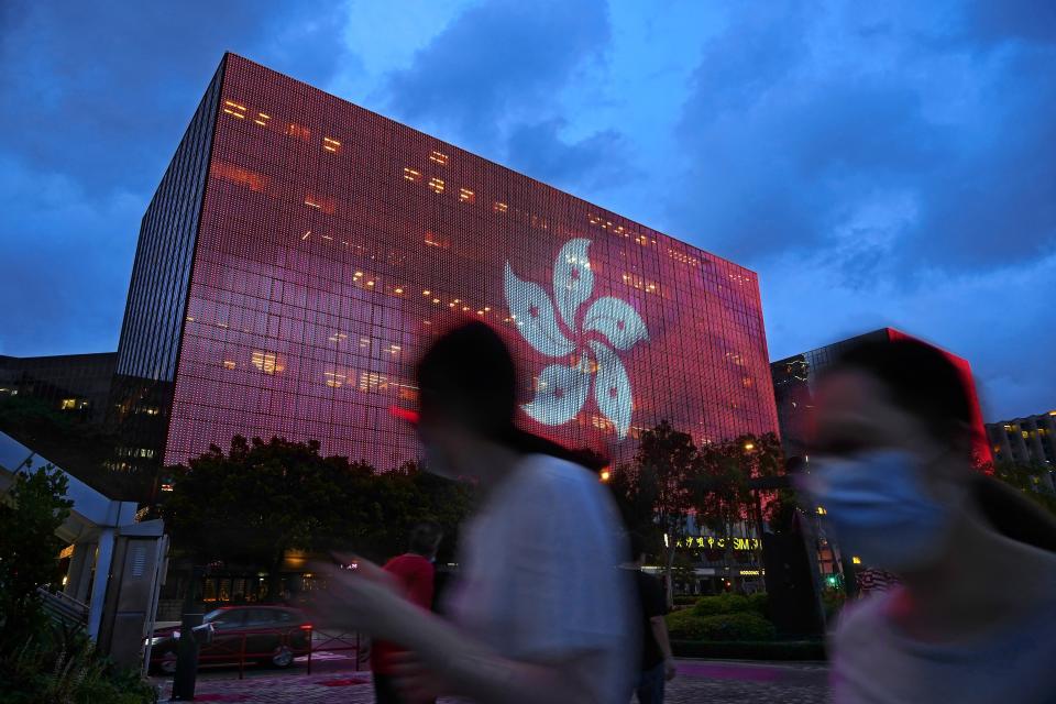 People walk past an electronic monitor showing a Hong Kong flag at a shopping district in Hong Kong Tuesday, June 29, 2021. A year after Beijing imposed a harsh national security law on Hong Kong, the civil liberties that raised hopes for more democracy are fading.(AP Photo/Vincent Yu)