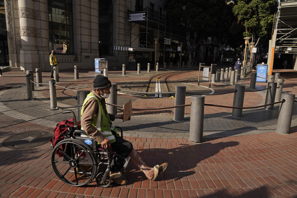 A man panhandling in a wheelchair, with open sores on his legs, makes his way past the Powell and Market Street cable car turnaround in San Francisco, Thursday, Dec. 2, 2021. In San Francisco, homeless tents, open drug use, home break-ins and dirty streets have proliferated during the pandemic. The quality of life crimes and a laissez-faire approach by officials to brazen drug dealing have given residents a sense the city is in decline. (AP Photo/Eric Risberg)