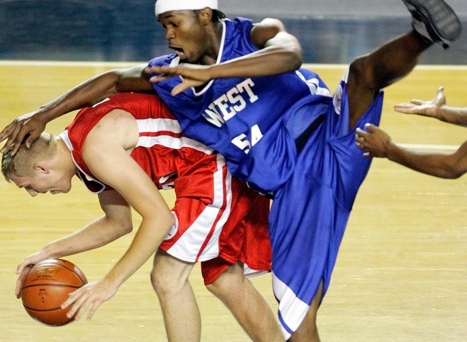 The West's Jerome Phillips (54), Chickasha, lands on the East's Tyler Parker (30), Fort Gibson, after trying to intercept a pass during the 2006 All-State Large Boys Basketball game in the Mabee Center at Oral Roberts University in Tulsa.