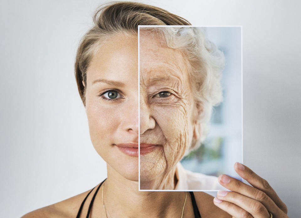 A woman holding an image of an older woman in front of half of her face